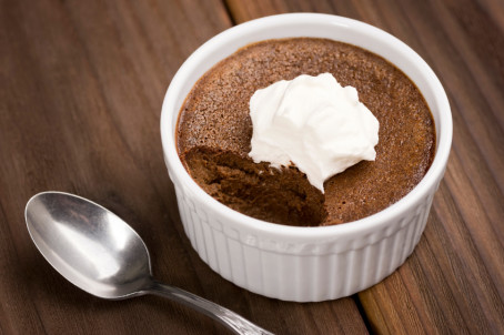 Chocolate Pot with whipped cream next to a spoon with one bite missing